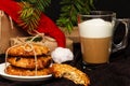 Christmas oatmeal cookies, mug of coffee with milk, gift boxes in kraft paper, hat of Santa Claus on brown background