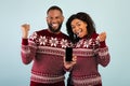 Christmas offer. Excited african american spouses celebrating success, showing smartphone with blank screen Royalty Free Stock Photo