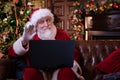 Christmas online congratulations from Santa. Santa Claus using notebook laptop for distance Christmas call kids sitting