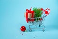 Christmas online shopping concept. Shopping cart with gifts, Christmas decor, Christmas tree on a blue background. background. 3d