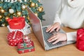 Christmas online shopping. Female buyer makes order on laptop. Woman buy presents, prepare to xmas, among gift boxes and packages Royalty Free Stock Photo