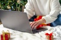 Christmas online shopping. Girl makes order on laptop. Woman buy presents, prepare to xmas, among gift boxes and Royalty Free Stock Photo