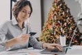 Christmas online shopping, young italian female holding plastic credit card and typing on laptop Royalty Free Stock Photo