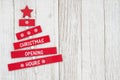 Christmas Opening Hours sign on red wood Christmas tree with weathered wood Royalty Free Stock Photo