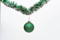 Christmas ornament concept. Ball with glamorous ornaments hang on shimmering green tinsel. Tinsel with pinned christmas