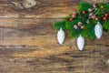 Christmas Ornaments hanging on green fir branch over rustic wooden board. Royalty Free Stock Photo