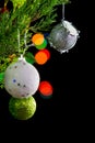 Christmas ornaments on pine tree branches. Colorful bokeh on black background Royalty Free Stock Photo