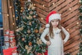 Disappointed little girl wearing Christmas costume standing isolated over wooden christmas background, keeping arms