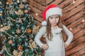 Disappointed little girl wearing Christmas costume standing isolated over wooden christmas background, keeping arms