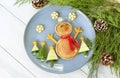 Christmas pancake shaped like snowman with fresh vegetablesn blue plate on wooden white table decorated festively Royalty Free Stock Photo