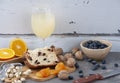 Christmas panettone slice with raisins and dried fruits on marble table. Orange slice, pistachio, blueberry, knife, nuts and dried