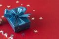 Christmas, party or birthday blue gift box or present with blue bow ribbon on red background Royalty Free Stock Photo