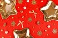 Christmas party flat lay with golden star shaped plates, bells, ribbons and snowflake ornaments on red background