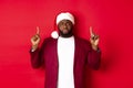 Christmas, party and holidays concept. Miserable and sad african american man pointing fingers up, looking disappointed Royalty Free Stock Photo