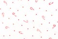 Christmas pattern made of candy cane and red shiny confetti on white background. Flat lay, top view.