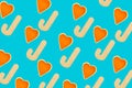 Christmas pattern made of wood candy stick and orange peel in shape of heart on blue background. Top view. Flat lay Royalty Free Stock Photo