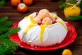 Christmas Pavlova cake with whipped cream, curd, tangerines and pomegranate on a dark wooden background. Copy space