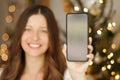 Christmas phone call and holiday greeting concept. Happy smiling woman showing screen of mobile smartphone, xmas