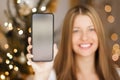 Christmas phone call and holiday greeting concept. Happy smiling woman showing screen of mobile smartphone, xmas