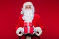 Christmas. Photo Santa Claus giving xmas present and looking at camera, on a red background