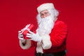 Christmas. Photo Santa Claus giving xmas present and looking at camera, on a red background