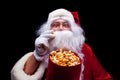 Christmas. Photo of Santa Claus gloved hand With a red bucket with popcorn, on a black background Royalty Free Stock Photo