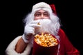 Christmas. Photo of Santa Claus gloved hand With a red bucket with popcorn, on a black background Royalty Free Stock Photo