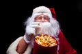 Christmas. Photo of Santa Claus gloved hand With a red bucket with popcorn, on a black background Royalty Free Stock Photo