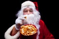 Christmas. Photo of Santa Claus gloved hand With a red bucket with popcorn, on a black background Royalty Free Stock Photo