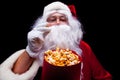 Christmas. Photo of Santa Claus gloved hand With a red bucket with popcorn, on a black background Royalty Free Stock Photo