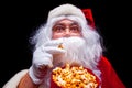 Christmas. Photo of Santa Claus gloved hand With a red bucket with popcorn, on a black background Royalty Free Stock Photo