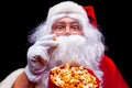 Christmas. Photo of Santa Claus gloved hand With a red bucket with popcorn, on a black background Royalty Free Stock Photo