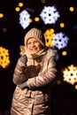 Girl holding yellow candy, lollipop. The New Year tree is lit with lights behind. Christmas photography