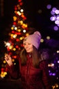 Christmas photography. the girl holds a sparkler in her hand, the lights of garlands on the tree are visible from behin