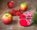 Christmas picture with warm socks with a christmas pattern, apples and branches of a christmas tree and rowan on a wooden