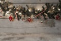 Christmas pine tree garland with red baubles, candy canes and ornaments, hanging on old wooden board background Royalty Free Stock Photo