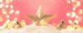 Christmas pink background with golden star. New Year`s decor. Christmas balls in smowdrifts and golden bokeh lights. Panoramic Royalty Free Stock Photo