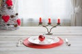 Christmas place setting with white dishware, cutlery, silverware and red decorations on white. Royalty Free Stock Photo