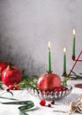 Christmas pomegranate candleholder with green burning candle.