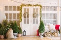 The Christmas porch is decorated with small Christmas trees and lanterns. Bench with pillows near the front door of the house Royalty Free Stock Photo