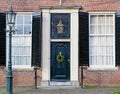 Christmas porch. House facade with vintage front door decorated with christmas wreath and antique shuttered windows. Black vintage