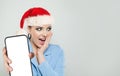 Christmas portrait of excited surprised woman in Santa hat showing smartphone with blank empty display screen Royalty Free Stock Photo