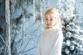 Christmas portrait of happy blonde child girl ndoor studio, snowy winter decorated tree on background. New Year Holidays