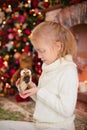 Christmas portrait of happy blonde child girl in white sweater holding toy owl near the Christmas tree and wooden toy horse. New Y Royalty Free Stock Photo