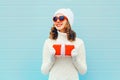 Christmas portrait happy smiling woman with gift box wearing a knitted hat sweater over blue Royalty Free Stock Photo