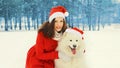 Christmas portrait happy woman with white Samoyed dog in red santa hat sitting on snow in winter day Royalty Free Stock Photo