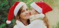 Christmas portrait of little girl child kissing her happy mother in santa red hat Royalty Free Stock Photo