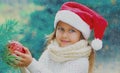 Christmas portrait smiling little girl child in santa red hat with ball toy outdoors Royalty Free Stock Photo