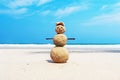 Christmas positive Sandy Snowman in red Santa Claus hat at ocean sunset beach. Royalty Free Stock Photo