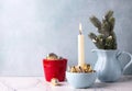Christmas postcard. Golden and silver cones decorations in red pot, white burning candle and fir tree branches in pitcher Royalty Free Stock Photo
